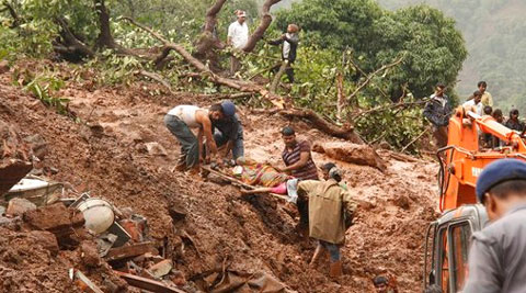 Rescue workers carry the body of a victim at the site of a landslide in Malin village. (Source: AP photo)