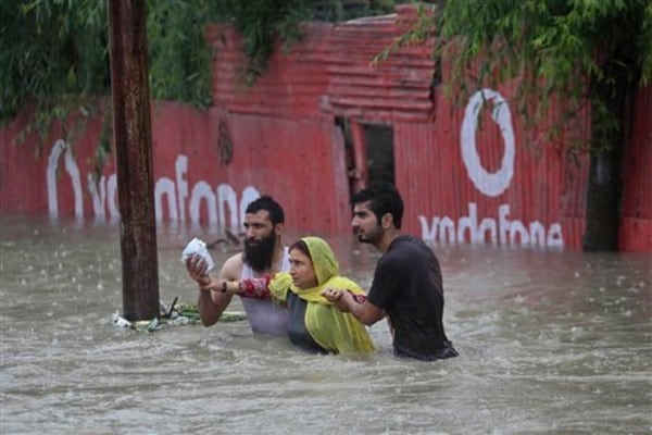 Kashmiri men help a woman move to a safer place after her neighborhood was flooded in Srinagar on Thursday. (AP photo)