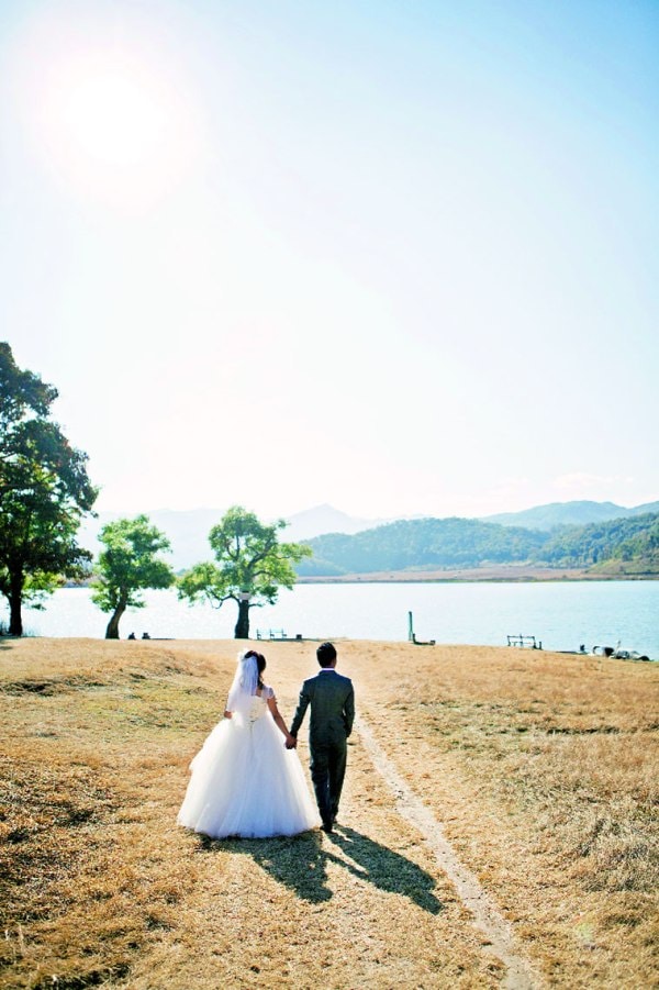 A bride and her groom walk towards the lake