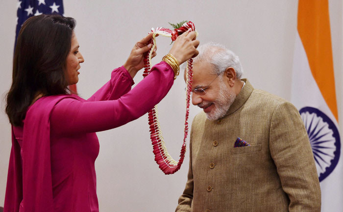 Gabbard, a 33-year-old US Democrat Congresswoman from Hawaii, called on the Prime Minister at his hotel. 	She presented to the Prime Minister a copy of Gita, which she had placed in her hand when she took oath while being sworn in to the US House of Representative. <br /><br /> Prime Minister Narendra Modi greeted with a garland by Member of House of Representatives Tulsi Gabbard during a meeting in New York on Sunday. (Source: PTI) 