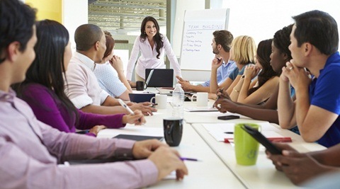 Businesswoman Addressing Meeting Around Boardroom Table