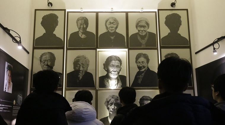 South Korea high school students look at portraits of late former "sex salves" who were forced to serve for the Japanese Army during World War II at the House of Sharing, the home for the living sex slaves, in Gwangju, South Korea, Tuesday, Dec. 29, 2015. A day after trumpeting an "irreversible" settlement of a decades-long standoff over Korean women forced into sexual slavery by Japan's WWII military, there's relief among South Korean and Japanese diplomats, fury among activists and many of the elderly victims and general public indifference in both countries. (AP Photo)