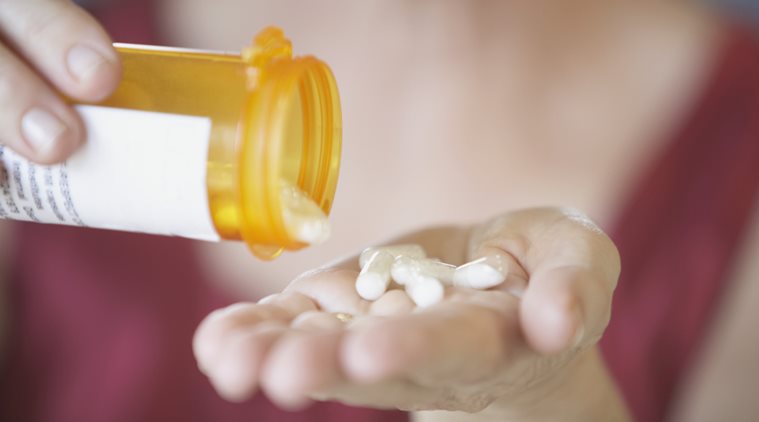 Close-up of a person's hands holding a bottle of pills