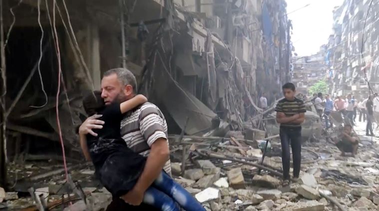 Un padre porta in salvo il figlio dopo un raid su Aleppo - Foto: AFP 