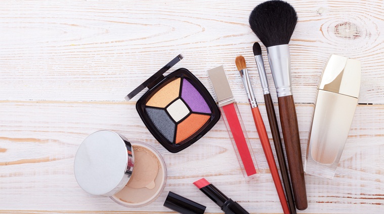 Colorful frame with various makeup products on white wooden background