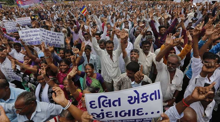 Hundreds of members of India's low-caste Dalit community take a pledge not to remove cattle carcass as they gather for a rally to protest against the attack on their community members in Ahmadabad, India, Sunday, July 31, 2016.Dalits have been protesting after four men belonging to their community were beaten while trying to skin a dead cow in Una in western Gujarat state early this month. Placard in Gujarati, front, reads, "Long Live Dalit Unity". (AP Photo/Ajit Solanki)