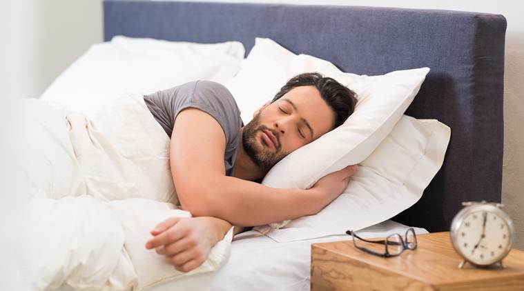 Handsome man sleeping in his bedroom. Man sleeping with alarm clock in foreground. Serene latin man sleeping peacefully.