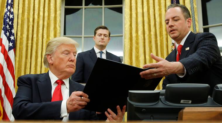 U.S. President Donald Trump hands Chief of Staff Reince Priebus (R) an executive order that directs agencies to ease the burden of Obamacare, after signing it in the Oval Office in Washington, U.S. January 20, 2017. Also pictured is White House Staff Secretary Rob Porter (C). REUTERS/Jonathan Ernst     TPX IMAGES OF THE DAY