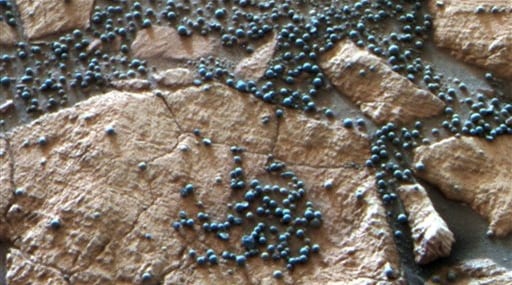 This image provided by NASA shows loose, BB-sized, hematite-rich spherules embedded in this Martian rock like blueberries in a muffin and released over time by erosion. 