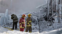 Police and firefighters survey the damage after a fatal fire at a seniors residence in L'Isle-Verte, Thursday. (AP)