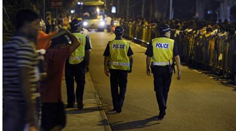 Police officers watch over migrant workers as they wait for shuttle buses to take them back their dormitories after spending their day off in Singapore's Little India District. (AP)