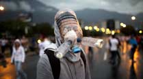 A protester wearing a gas mask made from plastic water bottles poses for a picture during an opposition protest blocking a highway outside La Carlota airport in Caracas, Venezuela. (AP Photo/Rodrigo Abd)