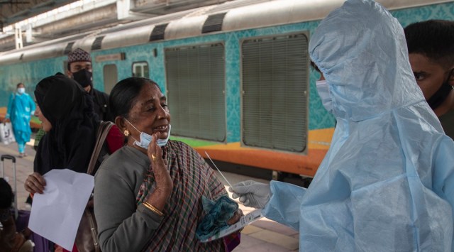 A health worker takes a swab sample of a traveler to test for COVID-19 at a train station in Mumbai. 
(AP/File)