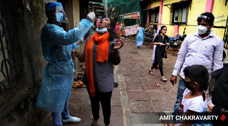 A healthcare worker takes swab sample of a woman in Mumbai on Saturday. (Express Photo: Amit Chakravarty)
