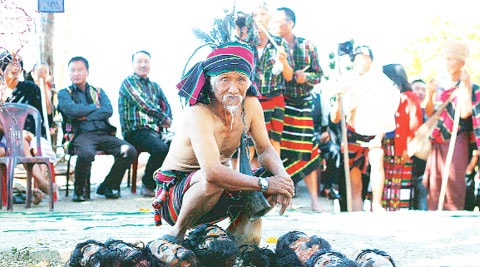 Men dressed as traditional Mizo warriors place artificial severed heads next to Sahlam tree.