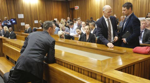 Olympic and Paralympic track star Oscar Pistorius talks to his brother Carl Pistorious (R) from the dock, ahead of the second day of his trial at the North Gauteng High Court in Pretoria (Reuters)