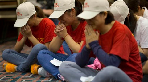 Relatives of Chinese passengers on board the Malaysia Airlines Flight 370 pray at a hotel conference room in Beijing, China. (AP Photo)