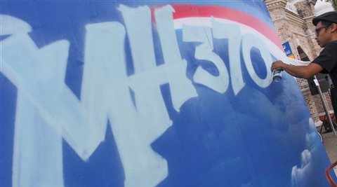A graffiti artist works on a graffiti featuring the missing Malaysia Airlines Flight MH370 in Kuala Lumpur. (Source: AP)