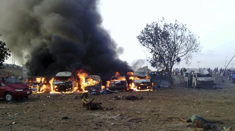 Victims of a blast lie on the ground as fire and smoke rise at a bus park in Abuja, Nigeria. (AP)