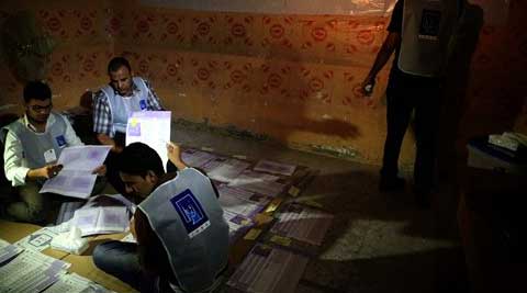 Electoral workers count ballots under lamplight due to a power cut, as polls close at a polling center in Basra. (AP)