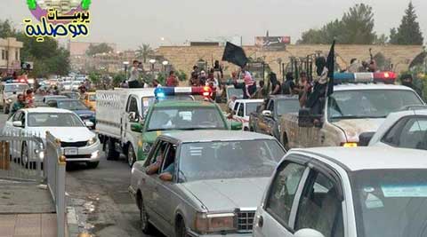 Militants wave the black flag as they parade down a main road in Mosul, Iraq in captured Iraqi Army and Police vehicles. (Source: AP)