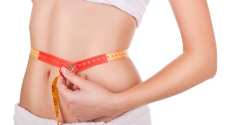 young woman's waist wrapped in a tape measure