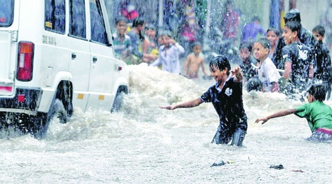 Children play in a waterlogged road during rain in Vadodara on Tuesday. (Express photo by Bhupendra Rana)