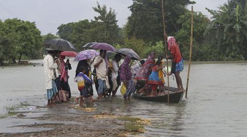 Flood affected villagers board a country boat at Gagolmari village in Morigaon district of north eastern Assam on Sunday. (Source: PTI)