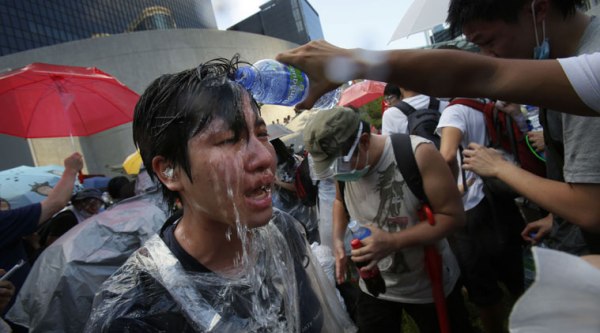 A student protester is overcome by pepper spray from riot police as thousands of protesters surround the government headquarters in Hong Kong Sunday, Sept. 28, 2014. (Source: AP)