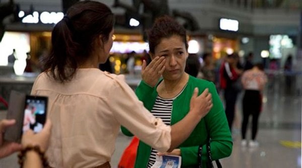 Guzulnur, wife of detained Uighur scholar Ilham Tohti cries as she bids farewell to friends before leaving on a flight for Urumqi (Source: AP)