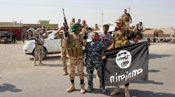 Shiite militiamen hold the flag of the Islamic State group they captured, during an operation outside Amirli, some 105 miles (170 kilometers) north of Baghdad, Iraq. Under the shadow of the Islamic State group threat, governments from France to Indonesia are moving aggressively to block would-be jihadis from taking their fight to Syria and Iraq. (Source: AP)