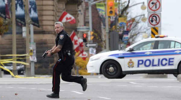 An Ottawa police officer runs with his weapon drawn outside Parliament Hill in Ottawa on Wednesday. (Source: AP photo)