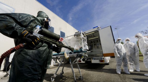 Participants into a course to learn how to transport and handle contagious patients, stand near an 'Aircraft Transit Isolator' (ATI) during a simulation at the military airport of Pratica di Mare, 30 kilometers south of Rome, Wednesday, Sept. 24, 2014. (Source: AP)