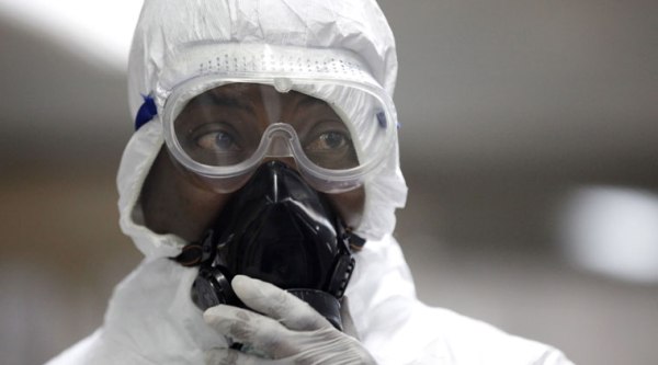 In this file photo, a Nigerian health official wearing a protective suit waits to screen passengers for the Ebola virus at the arrivals hall of Murtala Muhammed International Airport in Lagos, Nigeria. (AP Photo)