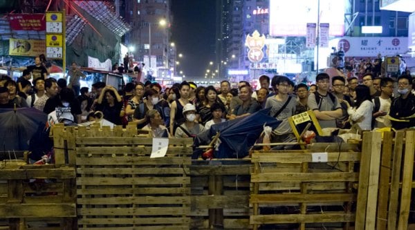 Protesters stand guard behind a barricade at the occupied area in the Mong Kok district of Hong Kong, early Monday, Oct. 20, 2014. Three weeks ago, students at a rally stormed a fenced-off courtyard outside Hong Kong's government headquarters, triggering unprecedented mass protests for greater democracy in the semiautonomous Chinese city. (Source: AP)