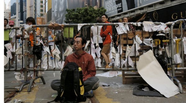 A protester rests after police removed barricades that protesters set up to block off main roads in Causeway Bay district in Hong Kong Tuesday, Oct. 14, 2014. (Source: AP)