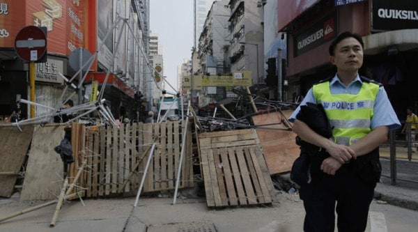 A police offer stands guard at a occupied area in a main roads in Mongkok district in Hong Kong Wednesday, Oct. 15, 2014. (Source: AP)