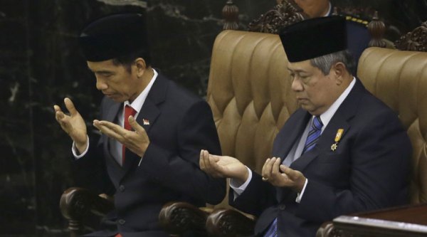 Indonesian President Joko Widodo, left, and his predecessor Susilo Bambang Yudhoyono pray during Widodo's inauguration ceremony as the country's seventh president at the Parliament building in Jakarta, Indonesia, Monday, Oct. 20, 2014. Widodo was inaugurated as Indonesia's new president on Monday, facing the challenges of rebooting a slowing economy and working with a potentially hostile opposition that has already landed some early blows against his administration. (Source: AP)