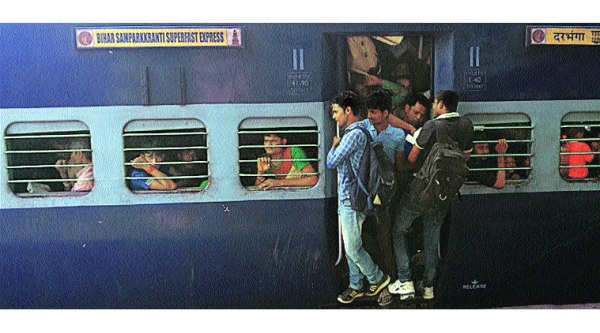 People travel on the footboard of a train bound for Bihar on Monday. ( Source: Express photo by: Praveen Khanna)