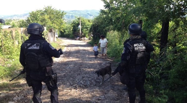 State police guard the road leading to the site where an alleged clandestine grave was found near the town of Pueblo Viejo, Mexico, Saturday, Oct. 4, 2014. (Source: AP)