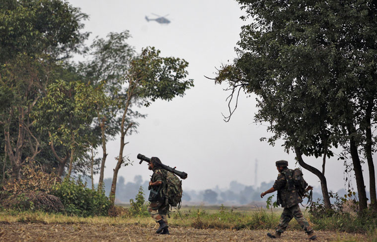 Indian Army soldiers walk at Pindi Khattar village in Arnia border sector, 43 kilometers (27 miles) south of Jammu, India, Thursday, Nov. 27, 2014. An army officer says some of the militants occupied an abandoned bunker in Jammu region early Thursday and fired at the soldiers in Arnia sector in the Indian portion of Kashmir. (AP Photo/Channi Anand)