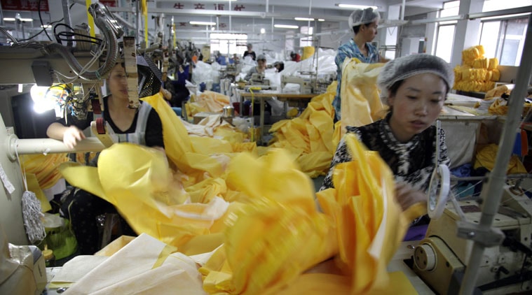 In this photo taken Thursday, Oct. 30, 2014, a Chinese worker manufactures protection suits that meet the standards for use by healthcare workers treating Ebola patients at a factory of U.S. based Lakeland Industries in Anqiu city in eastern China's Shandong Province. Chinese characters at top reads "Production". Far from the Ebola hot zone, the sewing and gluing machines at a factory in China have been whirring more than usual to produce crucial yellow suits that protect the front-line medics more than 11,000 kilometers (7,000 miles) away in West Africa. (Source: AP)