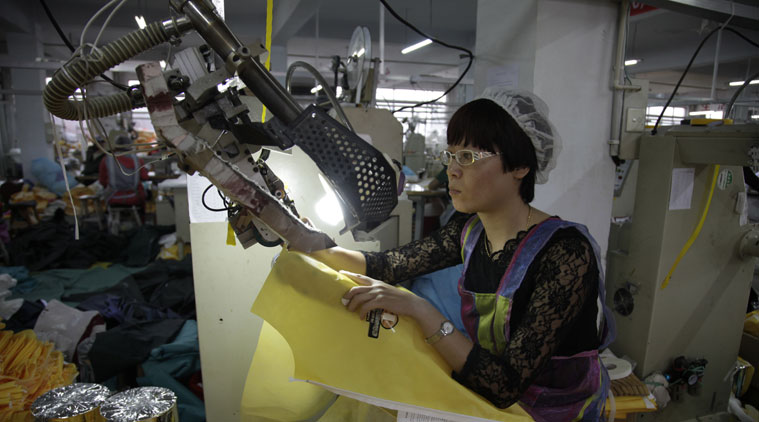 In this photo taken Thursday, Oct. 30, 2014, a Chinese worker manufactures protection suits that meet the standards for use by healthcare workers treating Ebola patients at a factory of U.S. based Lakeland Industries in Anqiu city in eastern China's Shandong Province. Far from the Ebola hot zone, the sewing and gluing machines at a factory in China have been whirring more than usual to produce crucial yellow suits that protect the front-line medics more than 11,000 kilometers (7,000 miles) away in West Africa. (Source: AP)