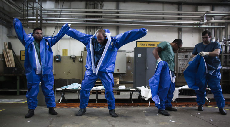 Volunteers of the German forces Bundeswehr put on their protective suits during a training for the Ebola virus in Appen about 25 kilometers (15,5 miles) north of Hamburg, Germany, Thursday, Oct. 23, 2014. The volunteers of the German forces Bundeswehr get trained for a mission to support the German Red Cross in Liberia in the fight against the Ebola epidemic. (Source: AP)