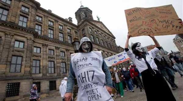 Anonymous supporters, one wearing a sign which reads "MH17 Stop The Cover Up" demonstrate outside the Royal Palace in Amsterdam, Netherlands, Wednesday, Nov. 5, 2014.  (AP Photo)