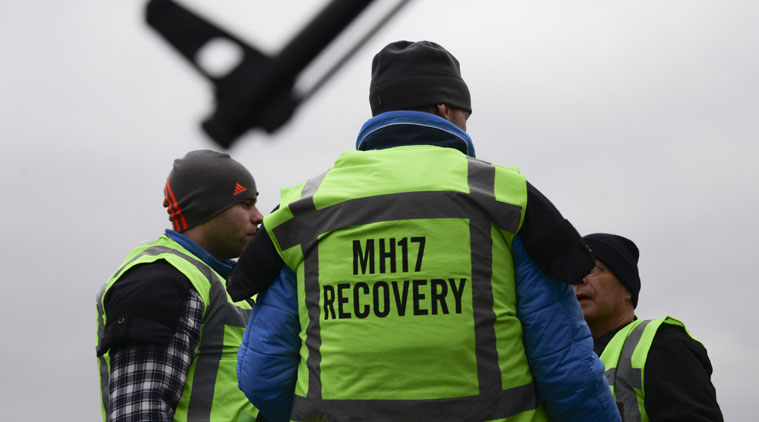 MH17 flight recovery team members talk to each as they are guarded by pro-Russian rebel fighter' in one of the areas of the Malaysia Airlines Flight 17 plane crash in the village of Hrabove, Donetsk region, eastern Ukraine Tuesday, Nov. 11, 2014. (Source: AP)