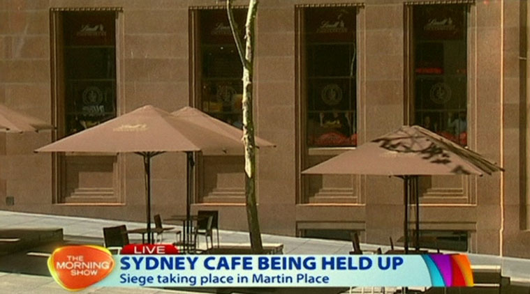 This image taken from video shows people against shop windows holding up hands inside a cafe in Sydney, Australia Monday, Dec. 15, 2014. An apparent hostage situation was unfolding inside the chocolate shop and cafe in Australia's largest city on Monday, where several people could be seen through a window with their hands held in the air. (AP Photo/Channel 7 via AP Video) 