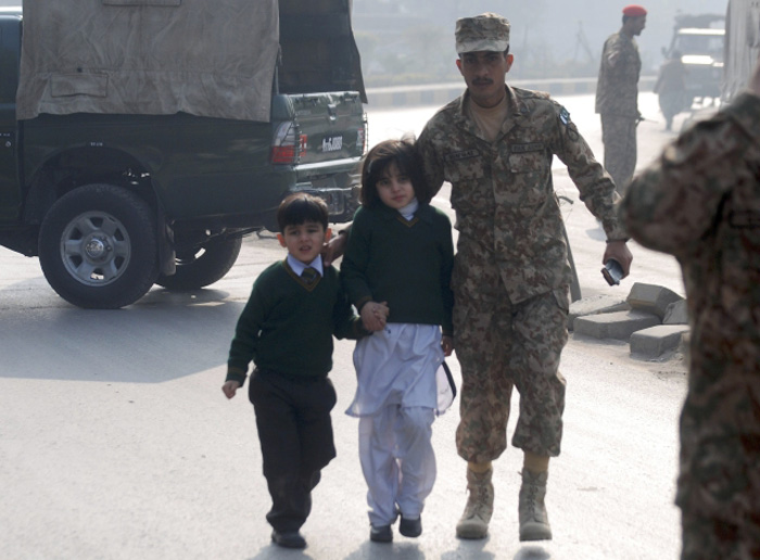 A soldier escorts schoolchildren from the Army Public School that is under attack by Taliban gunmen in Peshawar, December 16, 2014.  (Reuters) 