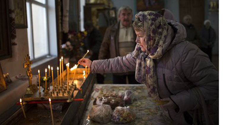 In this photo taken on Sunday, Oct. 26, 2014, a woman lights a candle before a service in the St. Olga and St. Vladimir Cathedral in Simferopol, Crimea. The property has come under threat from Crimea’s pro-Moscow leaders.