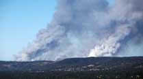 A plane flies over smoke from fires burring across the Adelaide Hills, near Adelaide, Australia, Saturday, Jan. 3, 2015. (Source: AP)